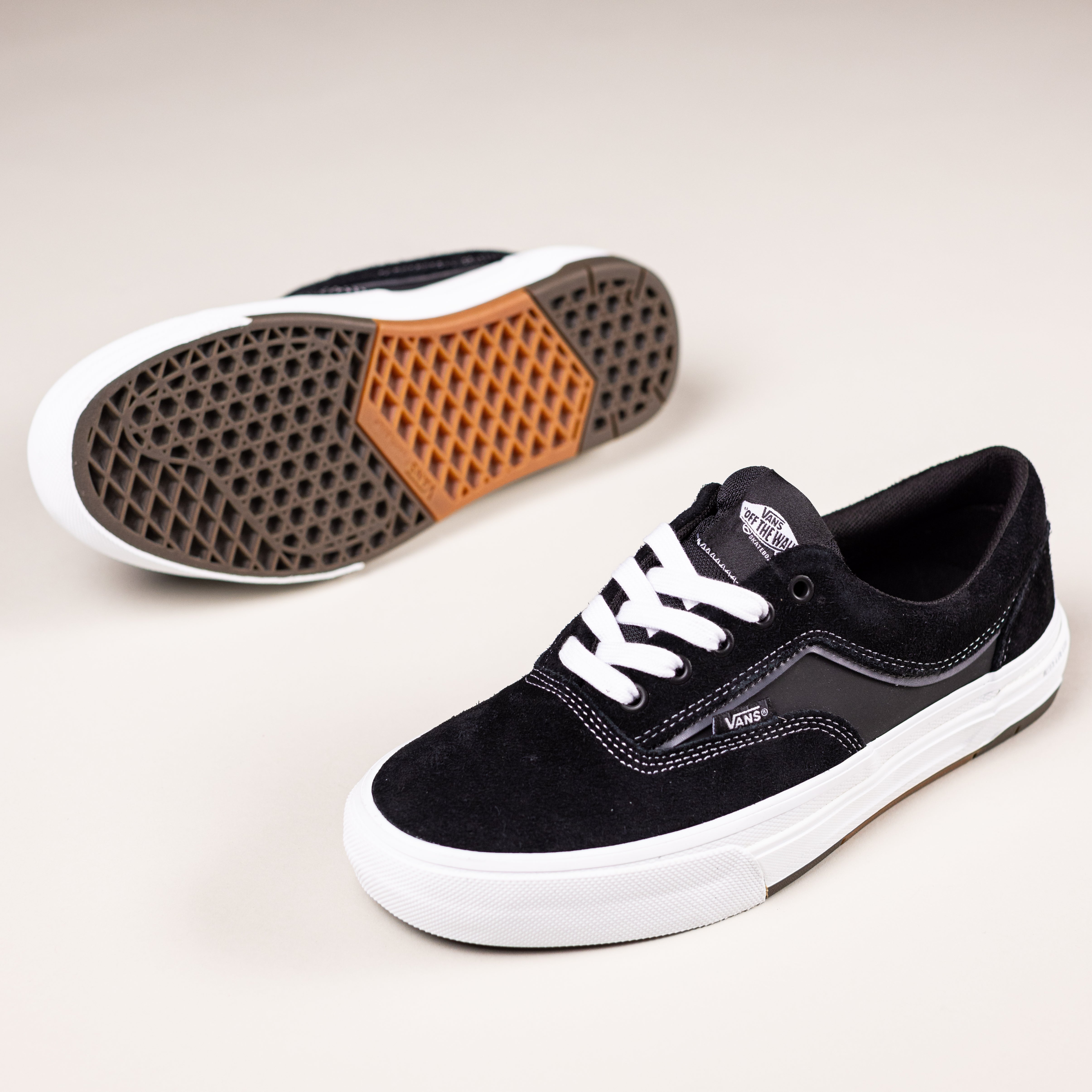 The Skate Era Wafflecup Black White VN000EF0BA21 Vans Suede Rubber Shoes are shown on a light background with DuraCap reinforcement. One displays the side, while the other highlights the signature brown waffle-patterned sole.