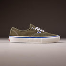 A single Suede Canvas Mossy Olive Authentic VN0A5FC8FR11 Vans Skate Skateboarding Shoe with white laces, stitching, a blue and white checkerboard logo, and white sole is shown in profile against a plain dark background.