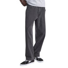 Someone stands with one hand in their pocket against a white background, wearing Vans Loose Denim Black VN000PH6BLK Skate Check 5 Pants in dark gray, a light gray shirt, and black-and-white sneakers.