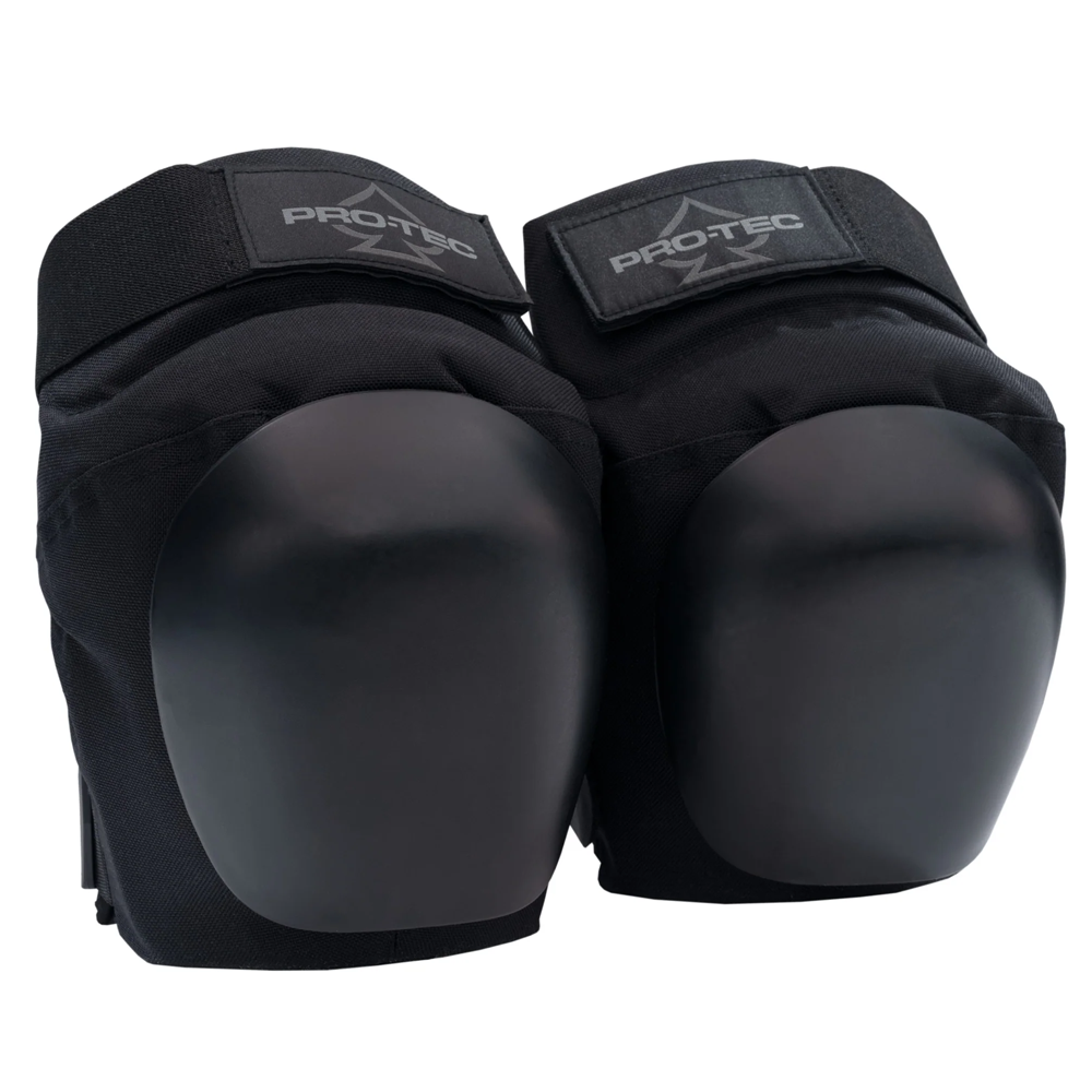 The Vert Knee Pads Protec Black are black skateboarding knee pads with hard, rounded plastic caps and adjustable velcro straps featuring the PROTEC logo, designed for vert skating protection.