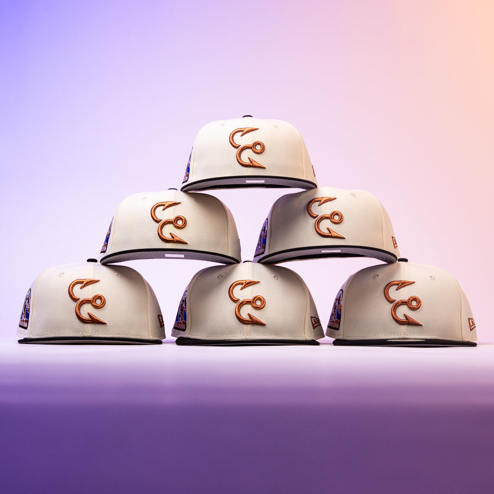 Six Warren 2.0 Hooks Chrome Black New Era Hat 5950 Fitted caps are stacked in a pyramid formation, their chrome black finish and signature style standing out against a vibrant purple and orange gradient background, showcasing the classic New Era fitted design.
