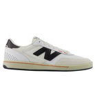 The White Black 440 NO2 New Balance Numeric Suede Skateboarding Shoes are white low-top sneakers featuring a black New Balance “N” logo, a black heel accent, white laces, and a beige sole with an orange stripe along the edge. Built for durability as a skate shoe, they include an ABZORB midsole that provides extra comfort and impact protection.