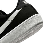Close-up of the heel and side of the Zoom Tennis Classic HF7386004 Black White Suede Nike SB Skateboarding Shoes, featuring a textured white sole, white stripe design, and part of the logo on the black suede heel.