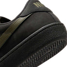 Close-up of the heel and side of the Nike SB Zoom Tennis Classic HF7386200 in Deep Pewter/Medium Olive suede, featuring a textured rubber sole, olive stripe detail, partial Nike branding on the back, and a cushioned insole for comfort.