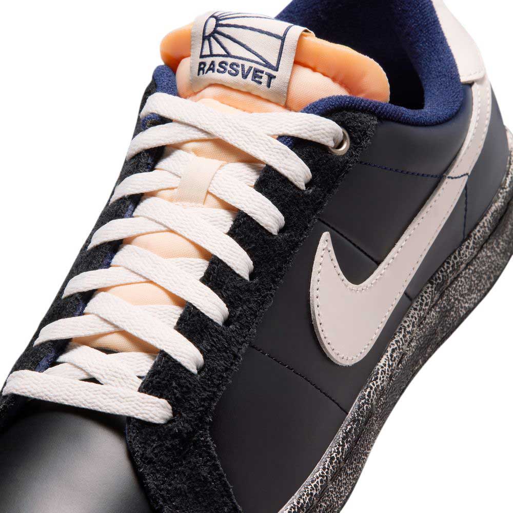 A close-up of the Nike SB Zoom Tennis Classic x Rassvet IO9846400 in Blue Void Sail with white swoosh, laces, black and gray panels, orange “RASSVET” tongue label, speckled midsole, and cushioned Solarsoft insole for comfort.