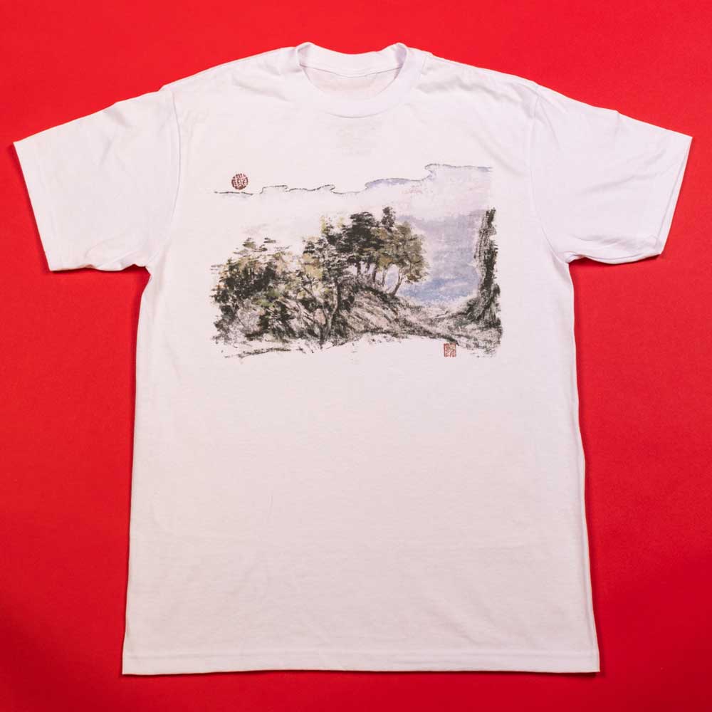 The Hillside Southside White Tee by Nguyen Duc Hien is a classic fit, soft USA cotton shirt with a front illustration of trees and a cloudy sky, shown laid flat on a solid red background.