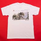 The Hillside Southside White Tee by Nguyen Duc Hien is a classic fit, soft USA cotton shirt with a front illustration of trees and a cloudy sky, shown laid flat on a solid red background.