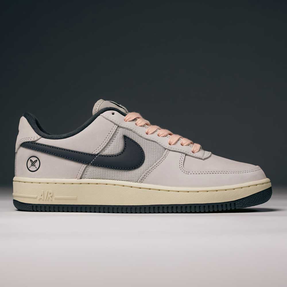 The Yuto AF1 Iron Grey White Coconut Milk IO8439100 Nike SB Suede Skateboarding Shoe features an iron grey suede upper with a contrasting black swoosh, a black outer sole, a light tan midsole, and soft light pink laces. Designed for both style and performance, it includes Nike Air cushioning to ensure all-day comfort. A small black circle with a line and X is detailed near the heel. Set against a dark gray background, this modern skate shoe embodies both innovation and street-ready appeal.