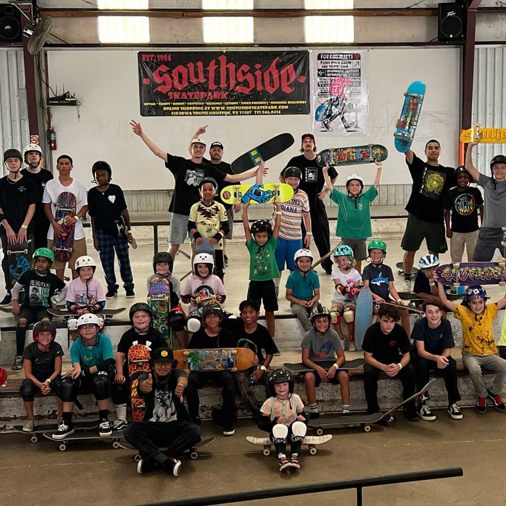Kids and teens pose with skateboards and helmets at Southside Skatepark during the Instructional Spring Break Skateboarding Day Camp, held March 9th-11th, 2026. Some smile and cheer in front of a camp banner.
