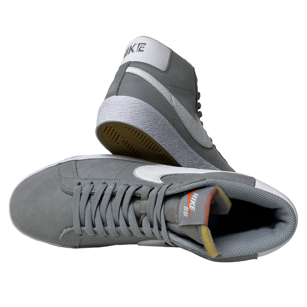 The Nike SB Blazer Mid DV5467001 White Wolf Grey Shoes showcase white swooshes and outsoles. One shoe stands upright and the other lies on its side, revealing the sole, inner lining, and tongue—all crafted for responsive cushioning.