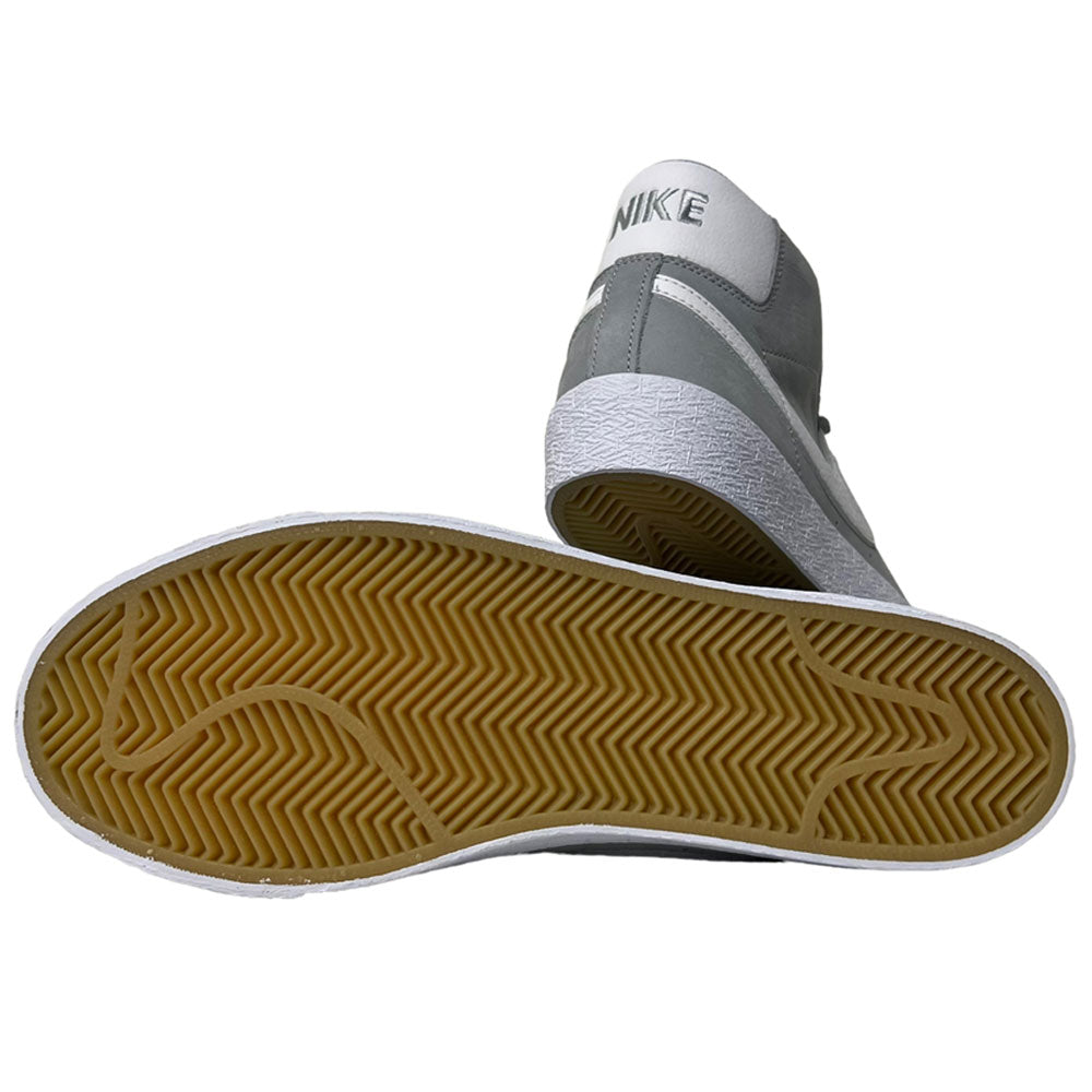 A pair of Nike SB Blazer Mid DV5467001 White Wolf Grey shoes—one upright showing the back, the other flat to display the textured light brown sole—ideal skateboarder sneakers with responsive cushioning.